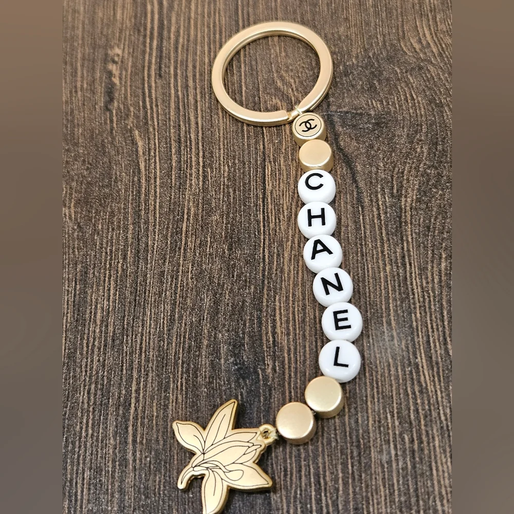 NIB CHANEL Sublimage Gold & White Beaded Keychain with Flower Charm